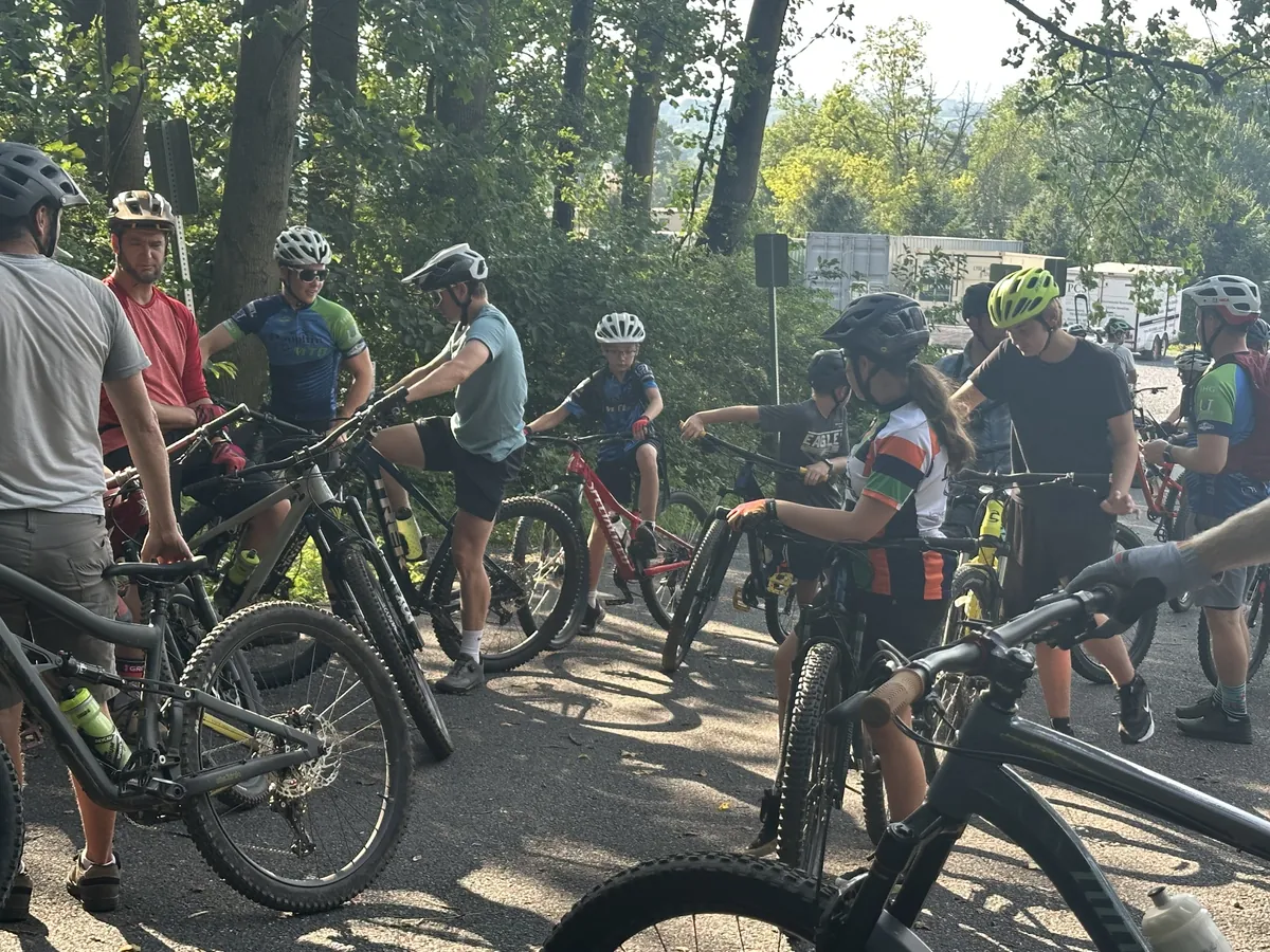 Riders and coaches gather with their bikes before a summer practice.