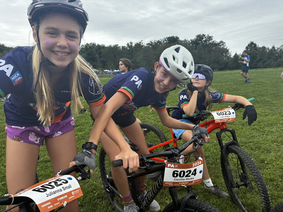 Three teammates share a smile with their bikes at a team event.